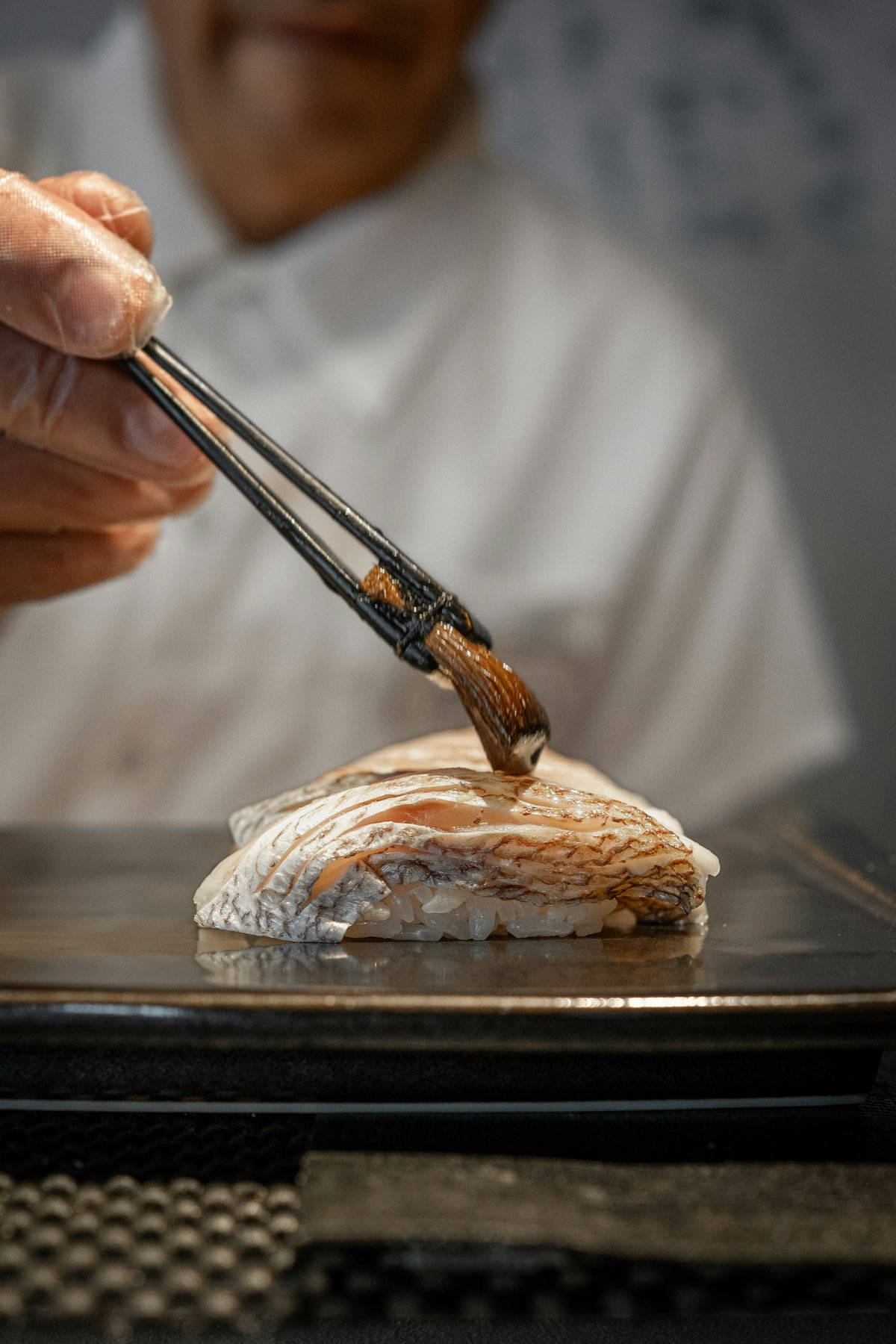 Chef brushing nikiri over nigiri